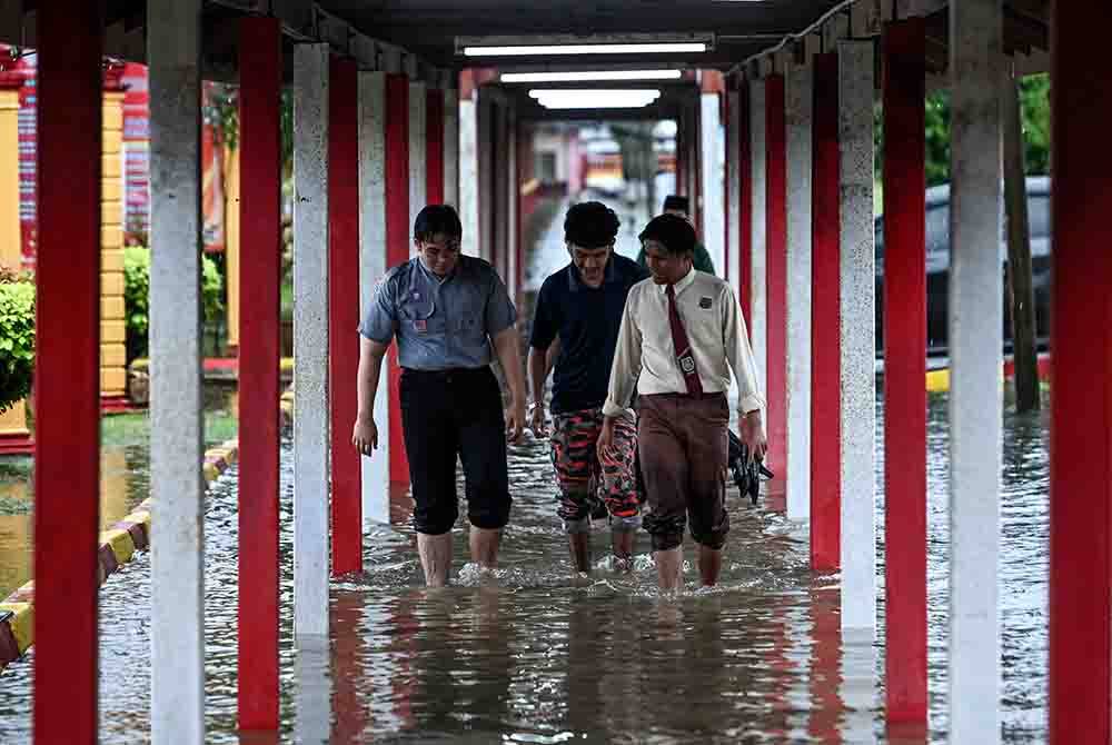 Beberapa pelajar Sekolah Menengah Kebangsaan Agama Sheikh Abdul Malek meredah banjir selepas sekolah itu ditenggelami air berikutan hujan lebat sejak malam tadi ketika tinjauan di Kuala Terengganu pada Selasa.