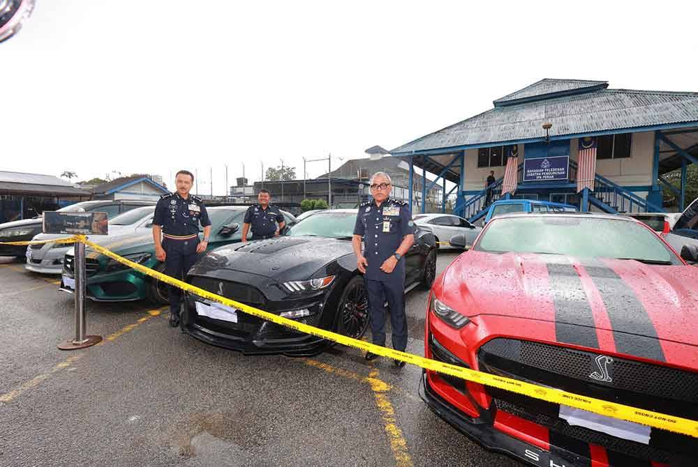 Ramli (kanan) menunjukkan antara kereta mewah yang dirampas hasil penahanan 11 individu sebuah sindiket pelaburan mata wang kripto tidak wujud di sebuah hotel di Ipoh.