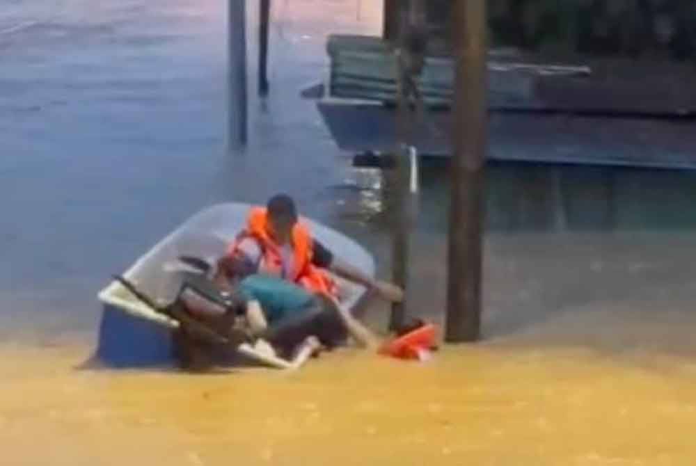 Anggota keselamatan menyelamatkan seorang wanita dan anaknya yang terperangkap banjir kilat di Pekan Sungai Lembing. Foto Bomba Pahang