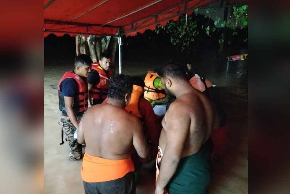 Anggota bomba memindahkan pengunjung dan sami selepas Kuil Sri Muniswarar Maha Mariamman dilanda banjir pada malam Rabu.