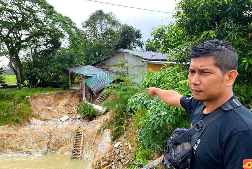 Che Yuosniza menunjukkan keadaan beranda rumahnya yang runtuh akibat hakisan tebing sungai di Kampung Lepah, Selising, Pasir Puteh pada Rabu.