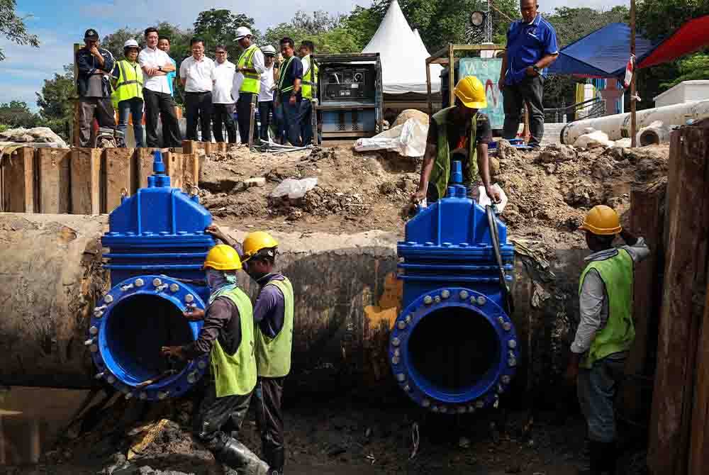 Kon Yeow (empat, kiri) meninjau kerja-kerja melibatkan penyambungan dua saluran paip 600 mm dan pemotongan sambungan 1,350 mm paip di bawah air yang dilaksanakan di Sungai Perai pada Khamis. Foto Bernama