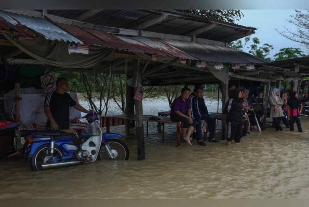 Penduduk setempat bersantai bersama jiran dan kenalan biarpun beberapa kawasan di sekitar Pasir Puteh digenangi air pada Rabu. Foto Bernama