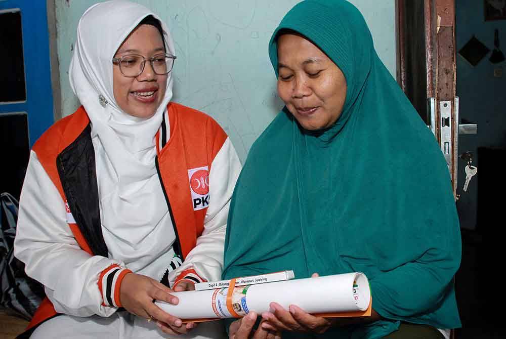 Lingga Permesti (kiri) dari Parti Parti Keadilan Sejahtera Islam (PKS) menyerahkan kalendar semasa kempen di bandar Klaten. - AFP