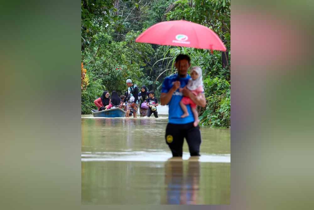 Penduduk meredah banjir untuk ke PPS semasa tinjauan di Kampung Besut hari ini. Foto Bernama