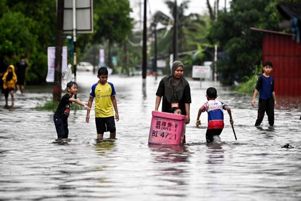 Penduduk di Jalan Kamaruddin, Kuala Terengganu meredah banjir selepas kawasan berkenaan dinaiki air berikutan hujan lebat pada Selasa. - Foto Bernama