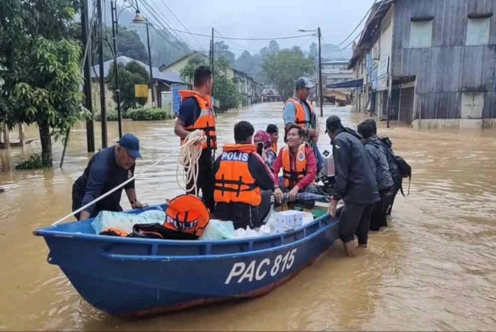 Mohd Shahar (tengah) menaiki bot bagi menyalurkan bantuan berupa makanan kepada mangsa yang terlibat dengan banjir di Pekan Sungai Lembing di Kuantan.