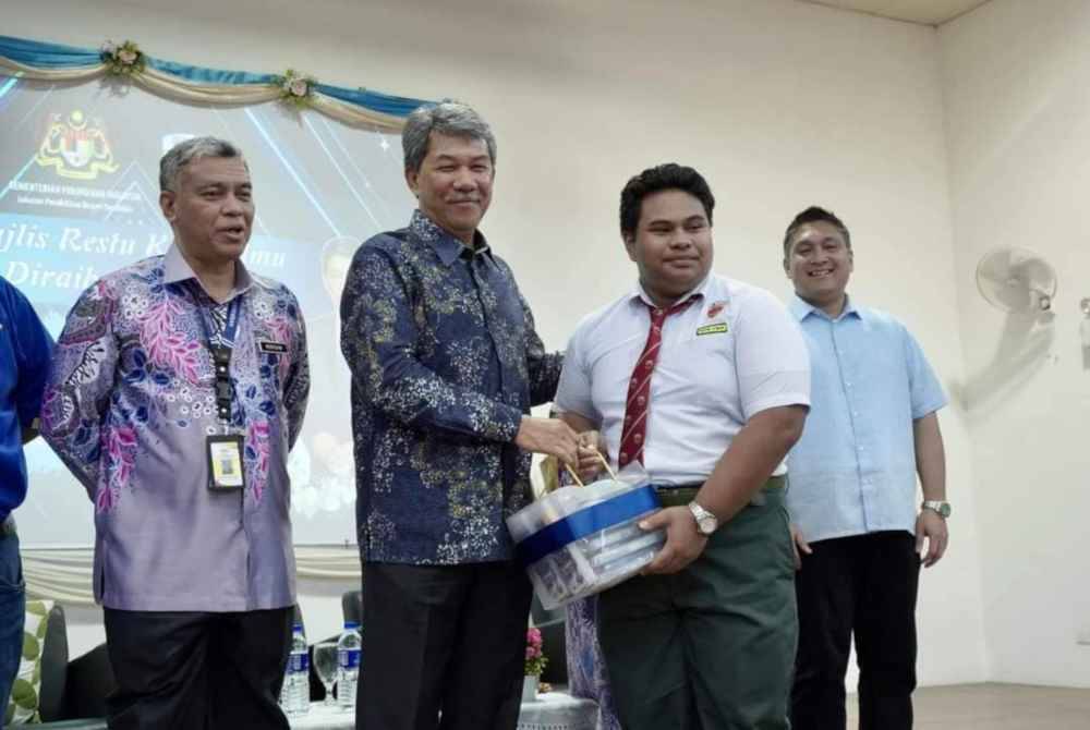 Mohamad (dua dari kiri) menyerahkan kit peperiksaan kepada calon SPM Sekolah Menengah Kebangsaan Bandar Baru Sri Sendayan.