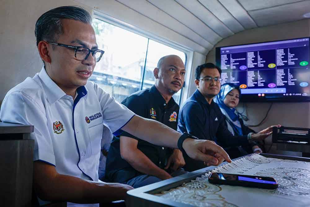 Fahmi (kiri) melihat Ujian Perkhidmatan Selular (Panggilan Suara) di Melaka River Cruise hari ini. Foto Bernama