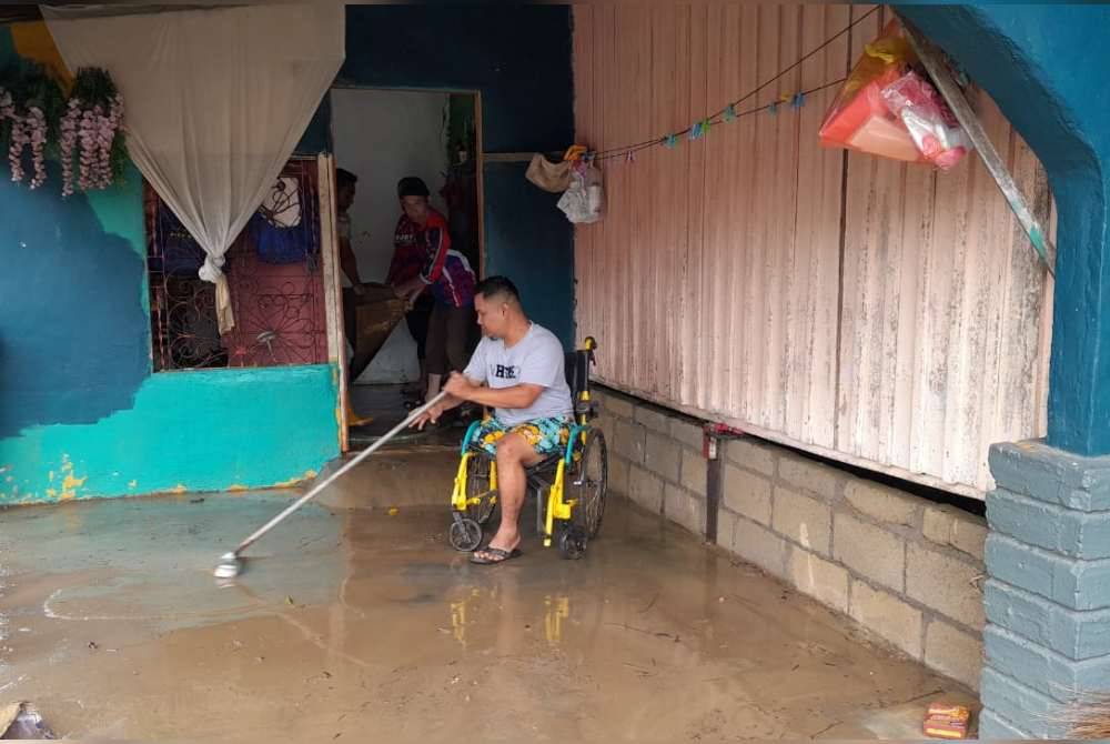 Muhammad Fadhil membersihkan rumahnya yang dilanda banjir di Felda Air Tawar 1, Kota Tinggi.