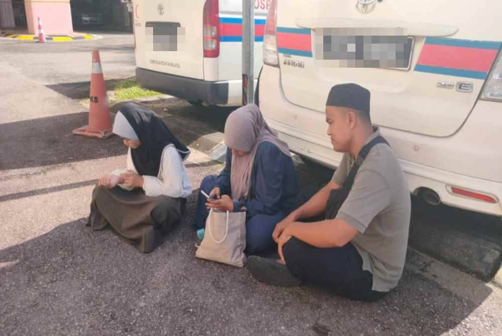 Noriah (tengah) bersama suaminya, Shahril Naim dan anak sulung mereka kita menunggu jenazah Muhammed Shafiq Aswad di pekarangan Unit Forensik HoSHAS Temerloh pada Sabtu.