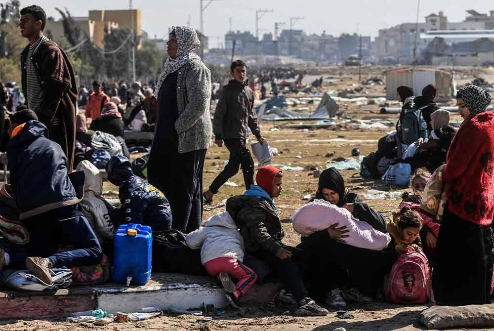 Penduduk Palestin menunggu di kaki lima ketika mereka melarikan diri dari Khan Yunis ke kawasan yang lebih selamat ke selatan di selatan Semenanjung Gaza. Foto AFP