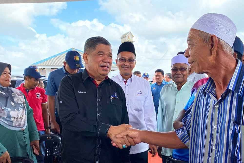 Mohamad (kiri) bersalaman dengan petani yang hadir pada Majlis Perasmian SMART SBB Ala Sekinchan KADA di bendang Tok Ajam di Pasir Puteh pada Ahad.