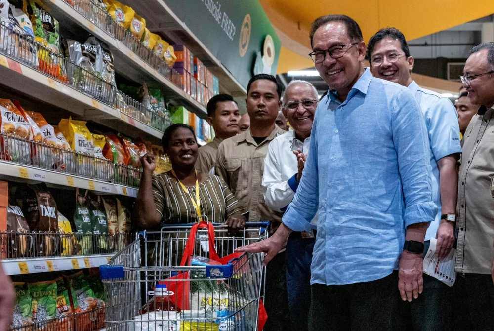 Anwar beramah mesra bersama penerima bantuan SARA ketika hadir pada program tersebut di Mydin Meru Raya, Ipoh. Foto Facebook Anwar Ibrahim