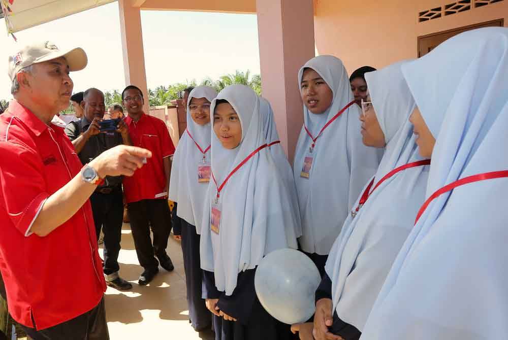 Ahmad Zahid kiri) menyantuni pelajar Maahad Abd Fatah Wa Abdul Jalil Tahfizul Quran Libanat, Selekoh pada Majlis Pecah Tanah Sekolah Menengah Imtiaz Tuminah Hamidi di Sungai Balai hari ini. Foto Bernama