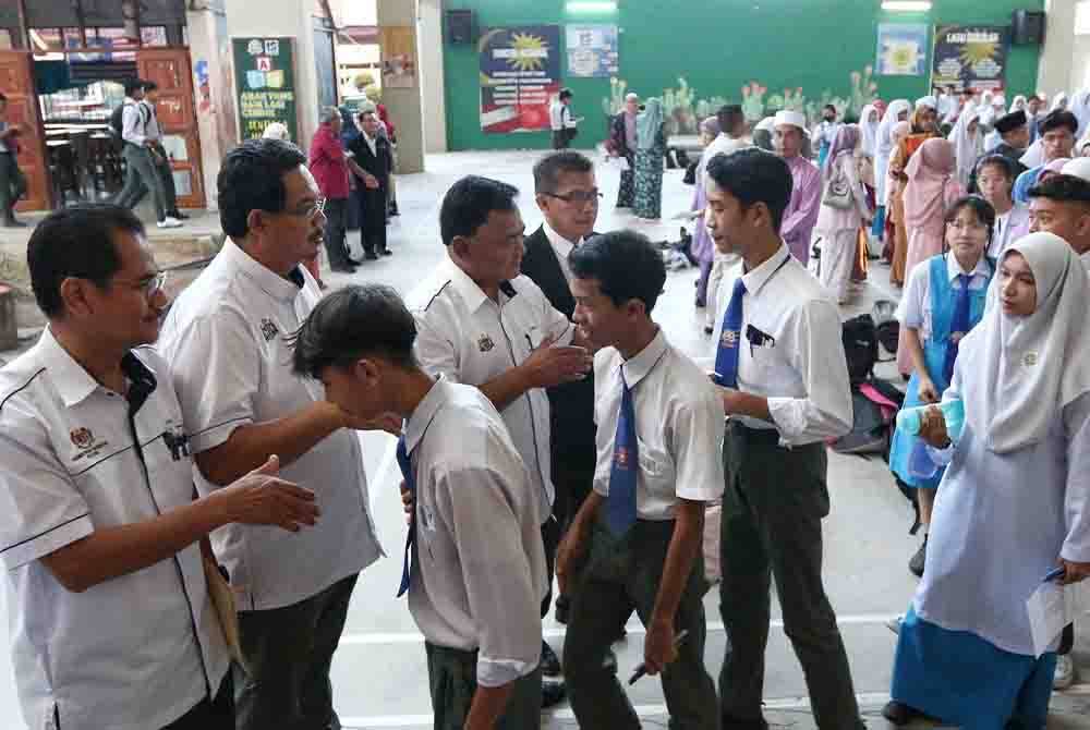 Rahmad (tiga,kiri) dan Rosli (dua,kiri) bersalaman dengan calon SPM sebelum mereka masuk ke dewan peperiksaan.