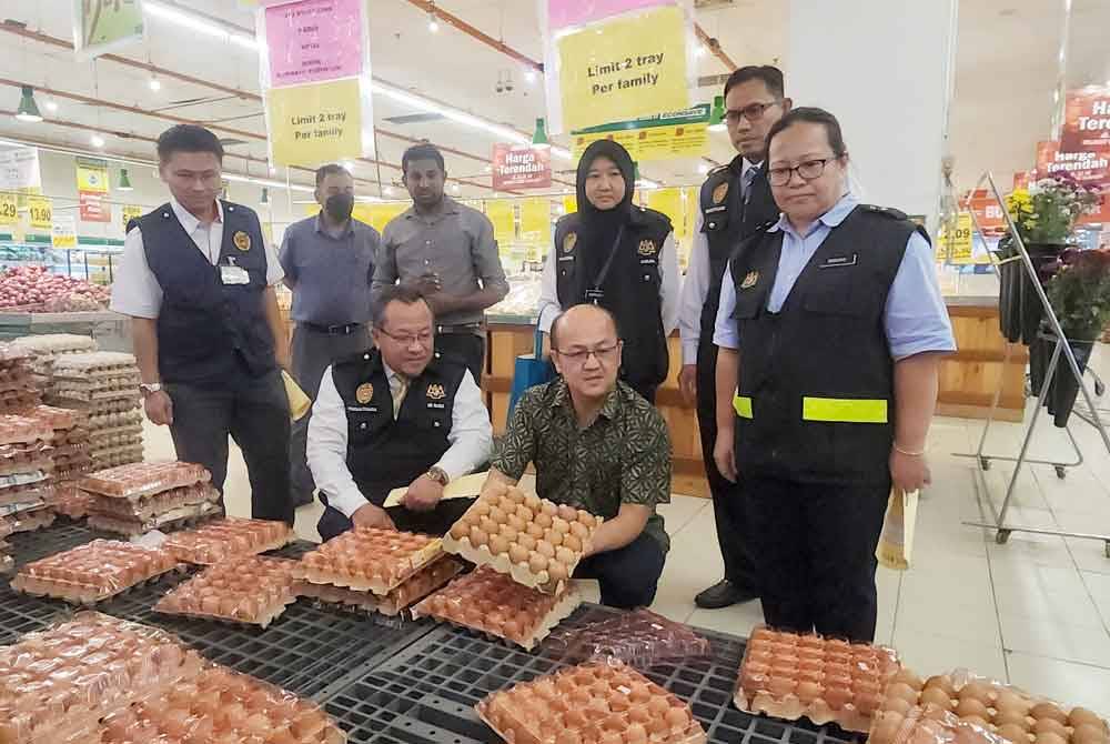 Rusid (depan, kiri) dan Hee Sem (dua dari kiri) menunjukkan beberapa biji telur ayam rosak ketika Operasi Tahun Baharu Cina di sebuah pasar raya di Batu Berendam pada Rabu.