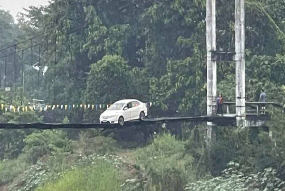 Sebuah kereta 'tersangkut' di sebuah jambatan gantung di Wiang Thong pada Isnin lalu. - Agensi