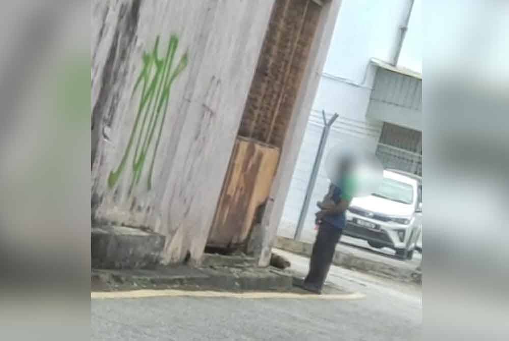 Tangkap layar individu yang memakai penutup kepala dan apron kencing di tepi longkang berdekatan Jalan Hang Tuah.