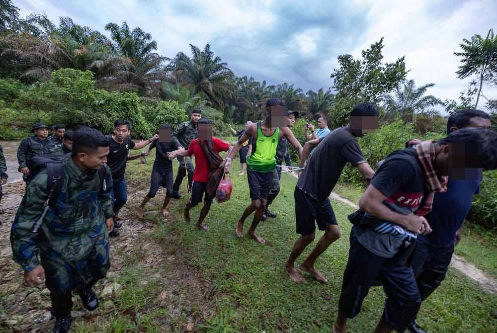 Seramai 13 pendatang asing tanpa izin yang meloloskan diri dari Depot Imigresen Sementara Bidor telah ditahan di sebuah kebun jambu di Kampung Senta hari ini. - Foto: Bernama