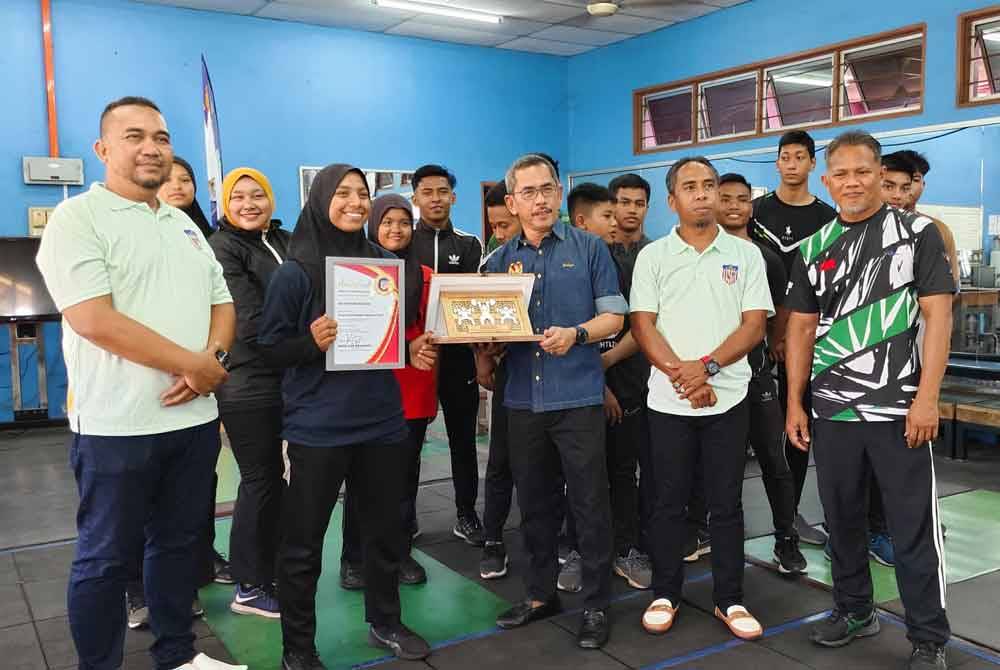 Nur Syazwani (depan, dua dari kiri) menerima anugerah atlet harapan PABM yang disampaikan oleh Yahaya di SMK Tunku Anum Tunku Abdul Rahman, Jitra pada Rabu.