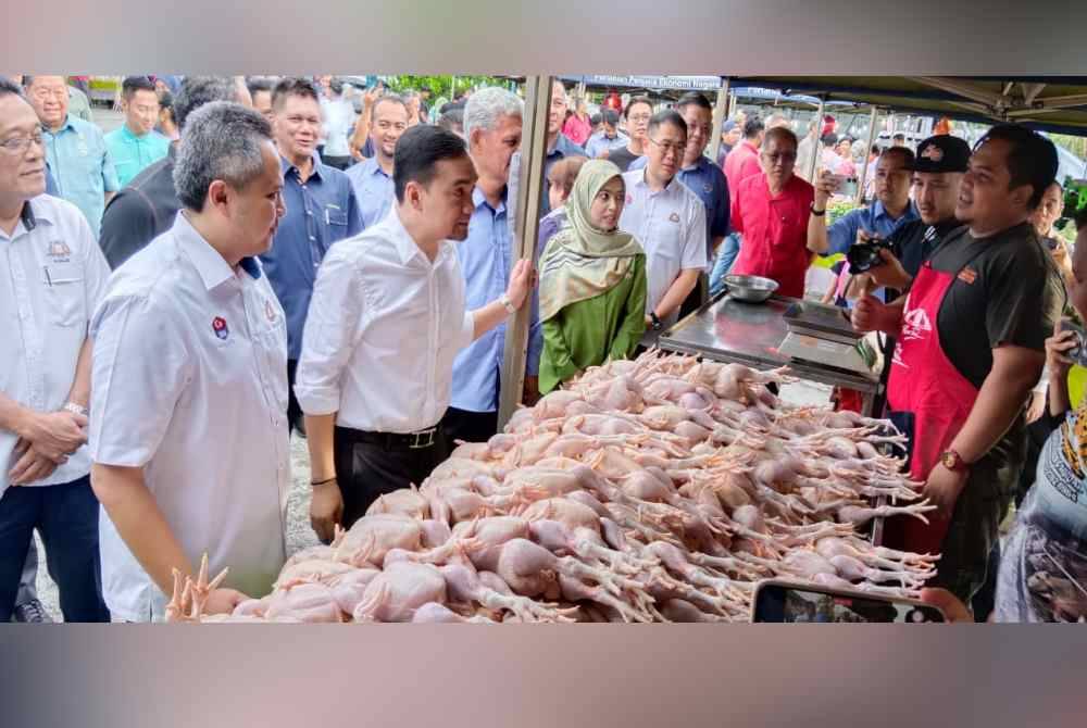 Onn Hafiz (tengah) meninjau harga ayam dalam Majlis Pelancaran Jualan Kasih Johor sempena Tahun Baharu Cina di Taman Johor, Johor Bahru pada Rabu.