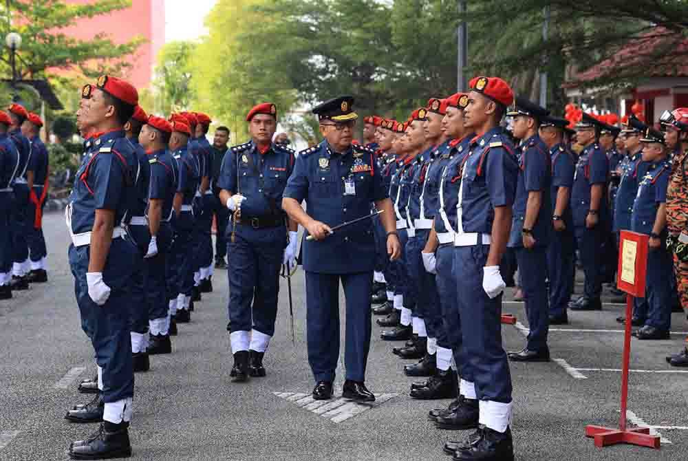 Zainal (tengah) memeriksa perbarisan anggota di JBPM di Tunjung, Kota Bharu.