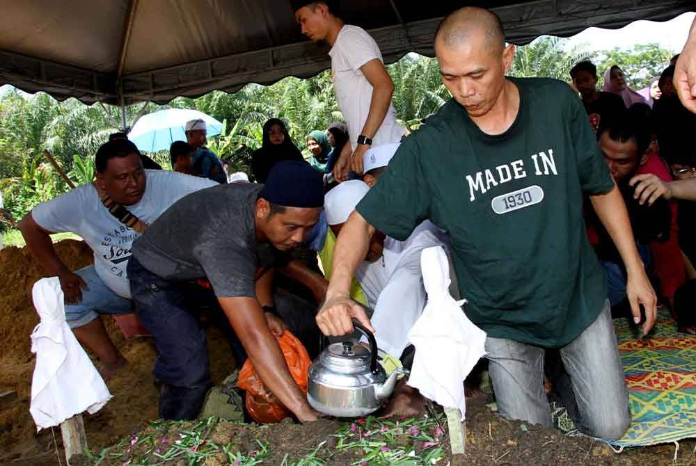 Azam menyiram air di pusara isterinya, Aszura di Tanah Perkuburan Islam Pekan Bidor, di Bidor, pada Khamis.