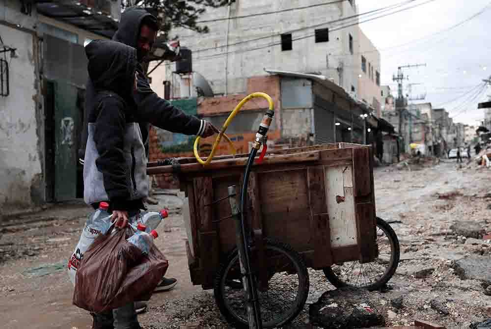 Penduduk Palestin menunggu untuk mengisi botol air di kem pelarian Tulkarem, Tebing Barat. Foto EPA