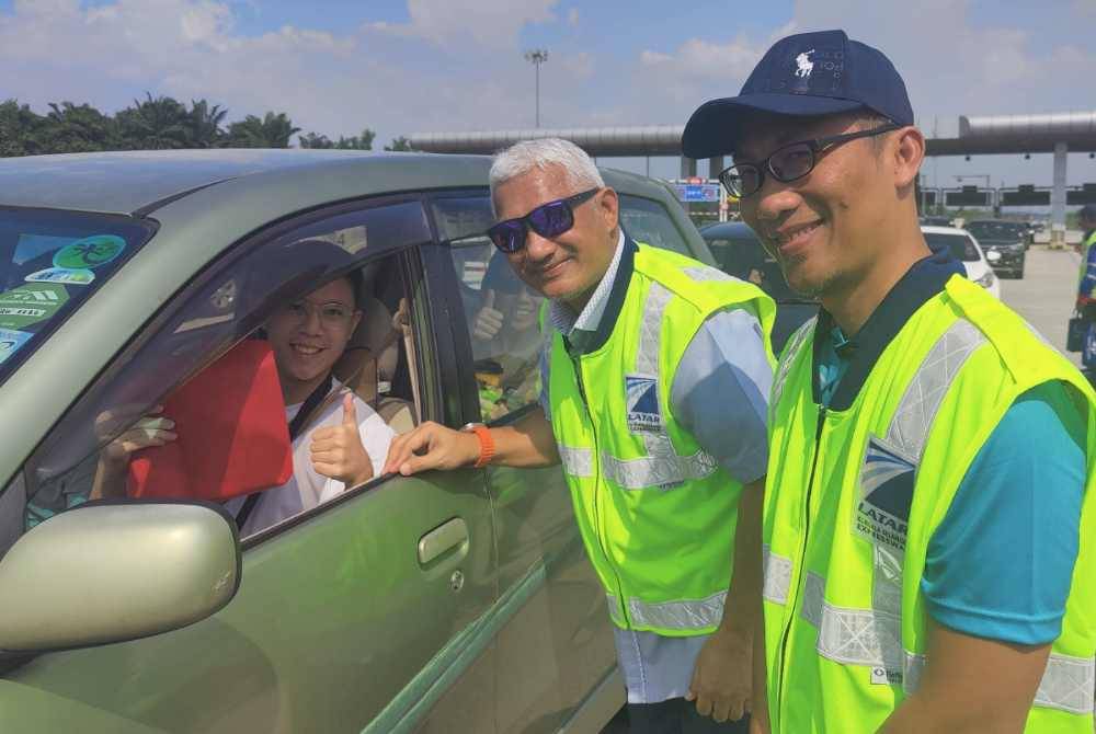 Ahmad Fuad (tengah) diiringi Yang Dipertua Majlis Perbandaran Kuala Selangor, Mohamad Hanafe Basri (kanan) menyerahkan cenderahati kepada pengguna jalan raya semasa Kempen Keselamatan Jalan Raya sempena Tahun Baharu Cina di Plaza Tol Ijok pada Khamis.