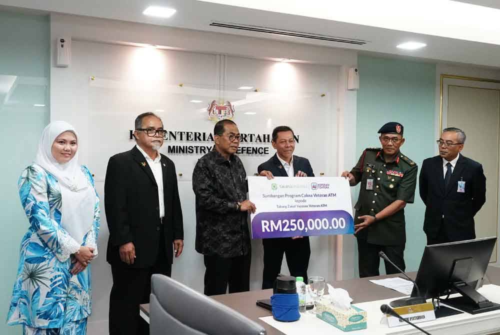 Mohamed Khaled (tiga dari kiri) menyerahkan replika cek daripada Takaful Malaysia berjumlah RM250,000 kepada Roba’i (dua dari kanan) pada satu majlis di Kementerian Pertahanan baru-baru ini.