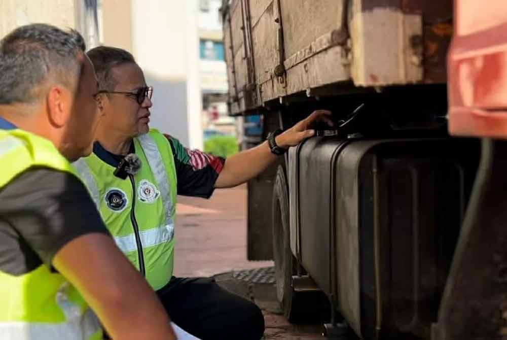 Azman (kanan) memeriksa tangki lori yang diubahsuai bagi mengaburi mata pihak berkuasa.