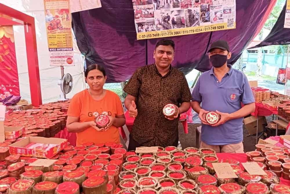 Balamurali (tengah) bersama isteri dan pekerjanya menunjukkan kuih bakul yang dijual di Bazar Tahun Baharu Cina di Taman Johor Jaya, Johor Bahru.