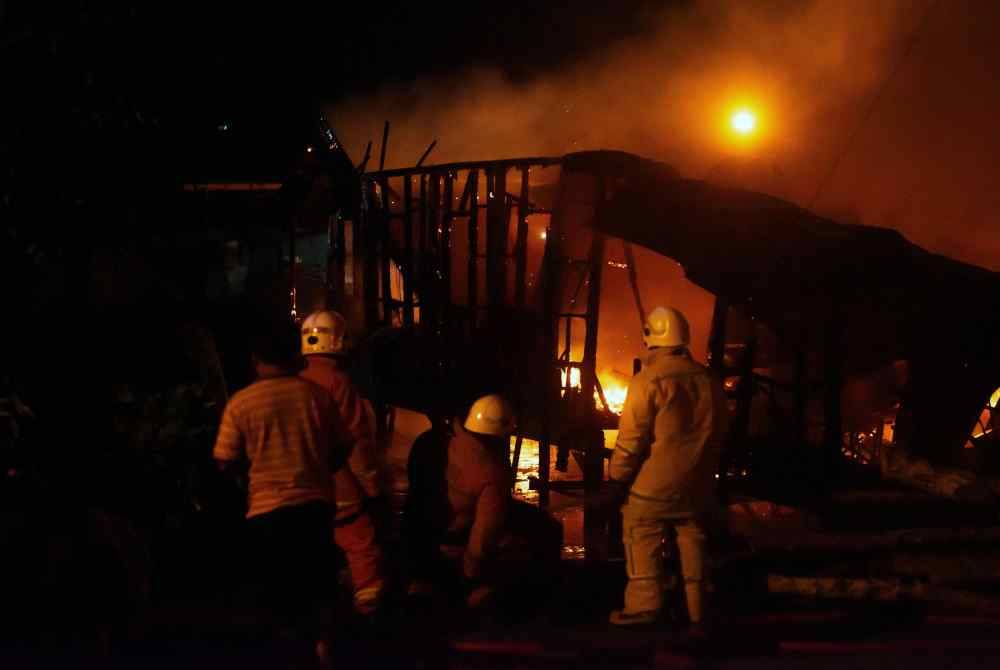 Anggota Jabatan Bomba dan Penyelamat Malaysia (JBPM) Labuan bertungkus-lumus memadamkan kebakaran dalam kejadian di Kampung Air Patau-Patau Dua pada malam Sabtu. Foto Bernama