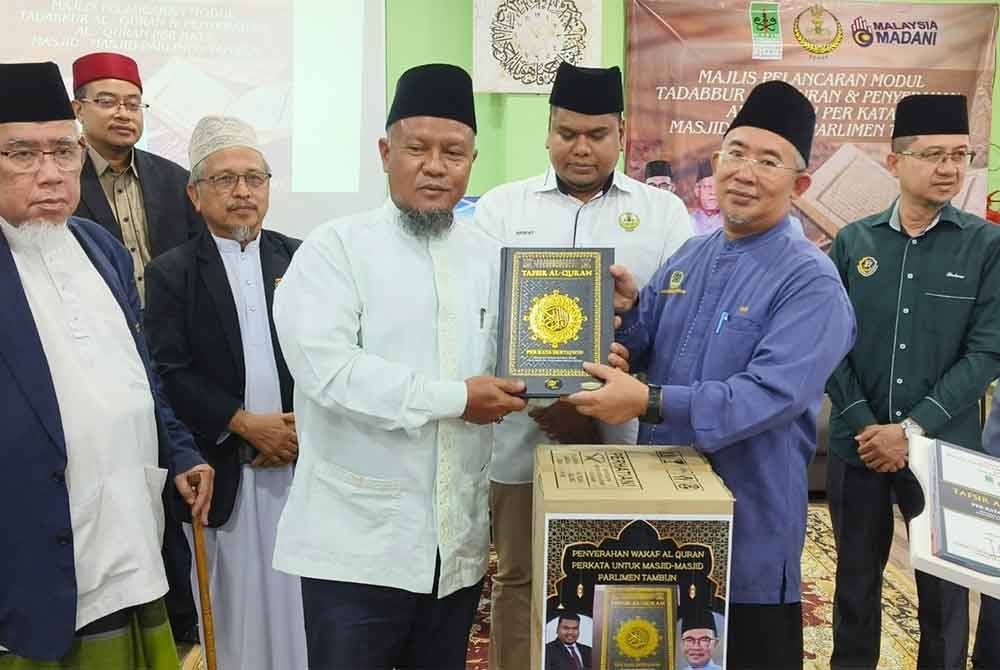 Mohd Azmi (kiri) menyaksikan majlis penyerahan al-Quran Perkata oleh Zamri (tiga dari kanan) kepada wakil masjid di Kompleks Pendidikan Baitul Ridzuan, Manjoi baru-baru ini.