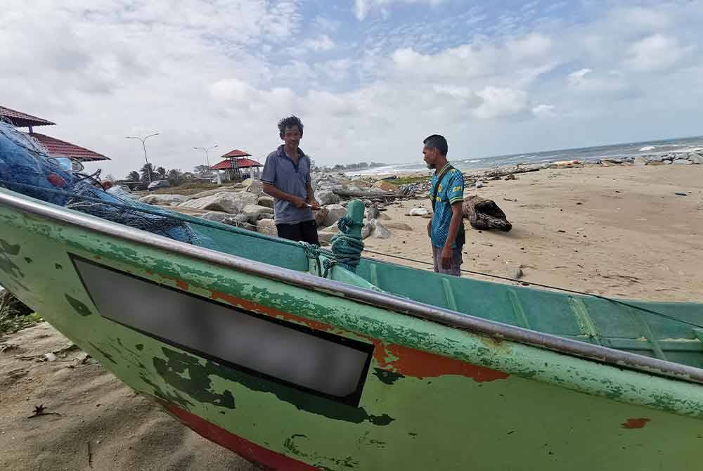 Zawawi (kiri) bersama Mohd Syukri (kanan) melihat bot yang rosak dan tersadai berhampiran jambatan angkat di Kuala Nerus.