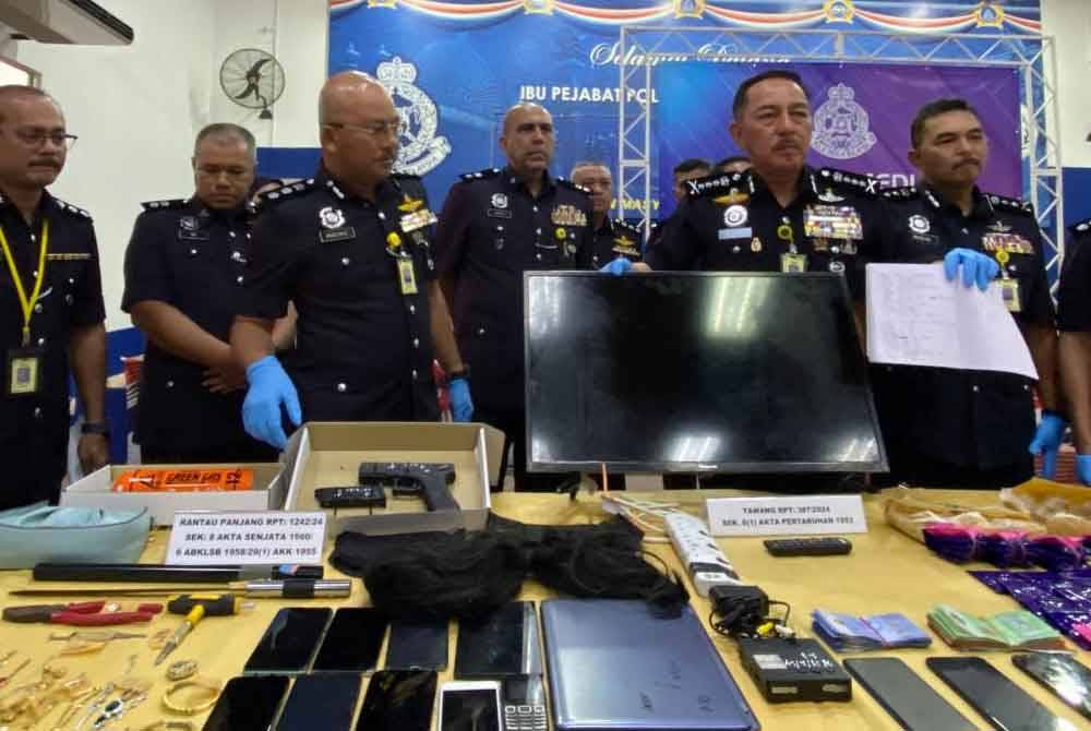 Muhamad Zaki (tiga dari kanan) menunjukkan barangan rampasan selepas menahan 15 lelaki di sebuah kedai makan di Kampung Beris Kubor Besar, Bachok pada Selasa.