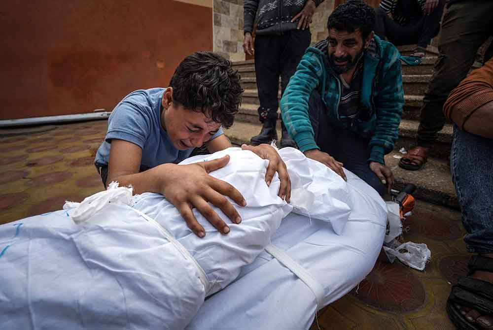 Seorang warga Palestin berkabung atas mayat saudara yang terbunuh dalam serangan Israel di hospital Nasser di Khan Yunis di selatan Semenanjung Gaza. - Foto AFP