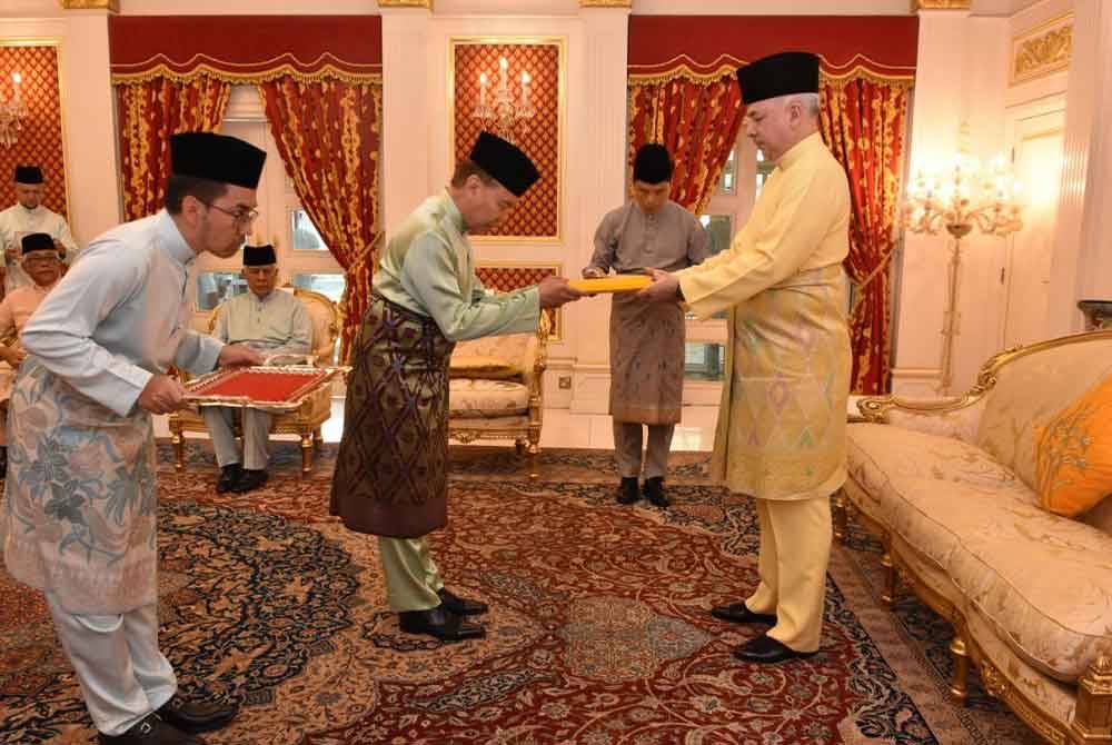 Sultan Nazrin (kanan) menyerahkan wang zakat perniagaan yang diterima daripada tiga syarikat korporat kepada Mohd Annuar di Istana Perak, Changkat Persekutuan pada Khamis.