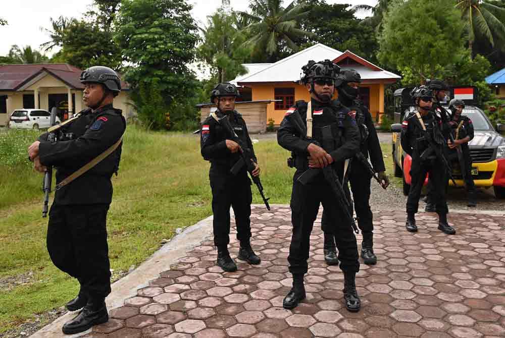 Polis berkawal berhampiran pusat mengundi sebelum pengundian dibuka dalam pilihan raya presiden dan perundangan Indonesia di daerah Kwamki Narama, kabupaten Mimika, Papua Tengah. Foto AFP