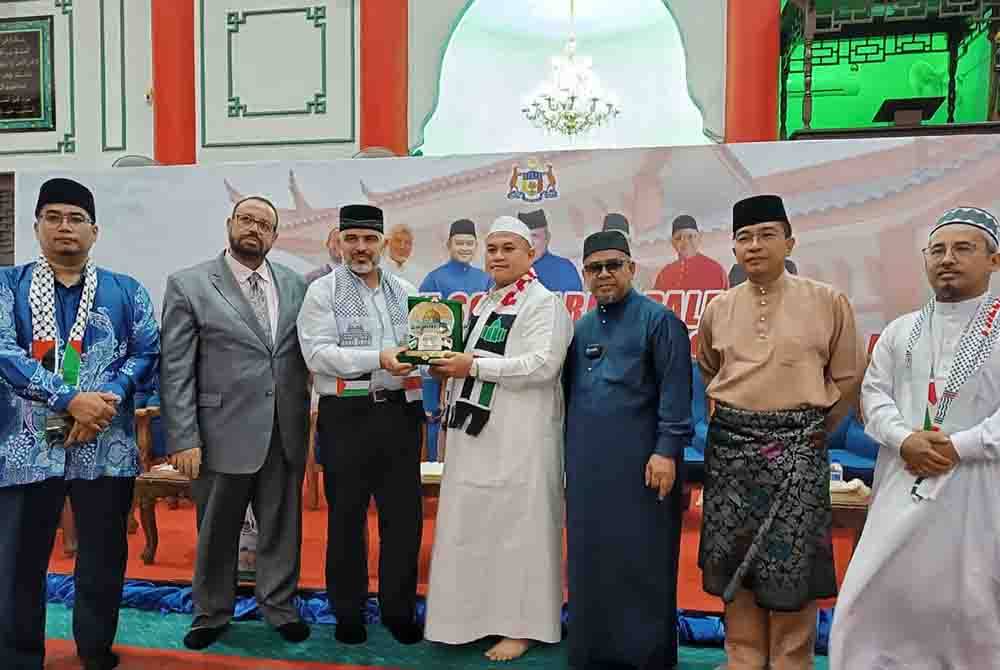 Aahid Abu Ata (tiga, kiri) menyampaikan cenderahati kepada Rais (empat, kiri) selepas Program Solidariti Palestin Sempena Sambutan Minggu Al Quds Sedunia, di Masjid Cina Krubong, di sini, pada malam Khamis.