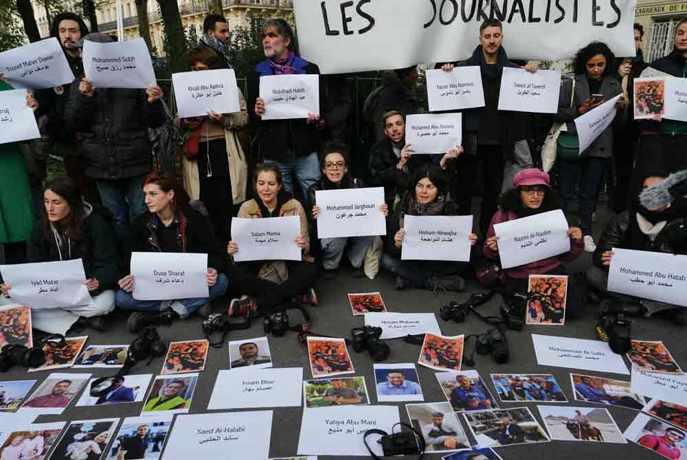 Penunjuk perasaan memaparkan nama wartawan yang terbunuh di Gaza sejak serangan balas Israel pada 7 Oktober lalu di Paris, Perancis. - AFP