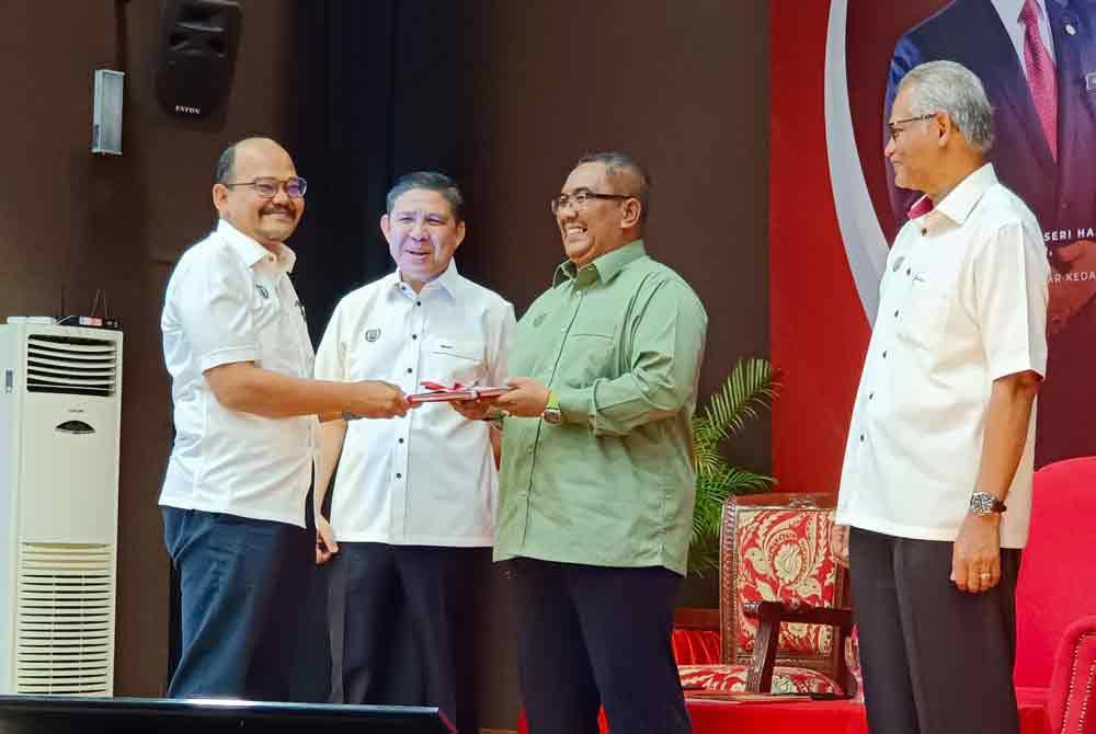 Muhammad Sanusi (dua kanan) menyerahkan buku bengkel pengurusan tanah pada Program Amanat Menteri Besar kepada Pentadbiran Tanah Negeri Kedah Tahun 2024 di Dewan Seri Mentaloon, pada Ahad.