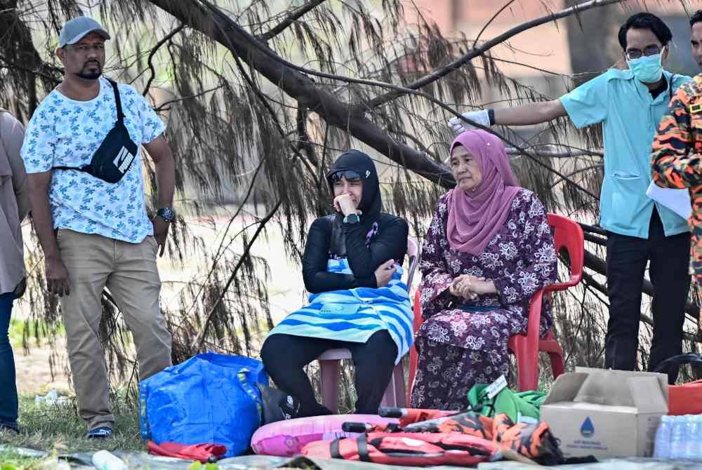 Isteri mangsa, Nora Elina (dua, kiri) tidak dapat menahan kesedihan selepas suaminya dikhuatiri lemas selepas dihanyutkan arus di Pantai Batu Buruk pada Ahad. Foto Bernama