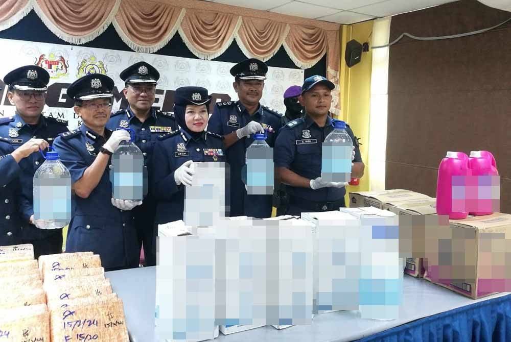 Nor Izah (tengah) menunjukkan air zam zam yang dirampas di ICQS Bukit Kayu Hitam pada Selasa.