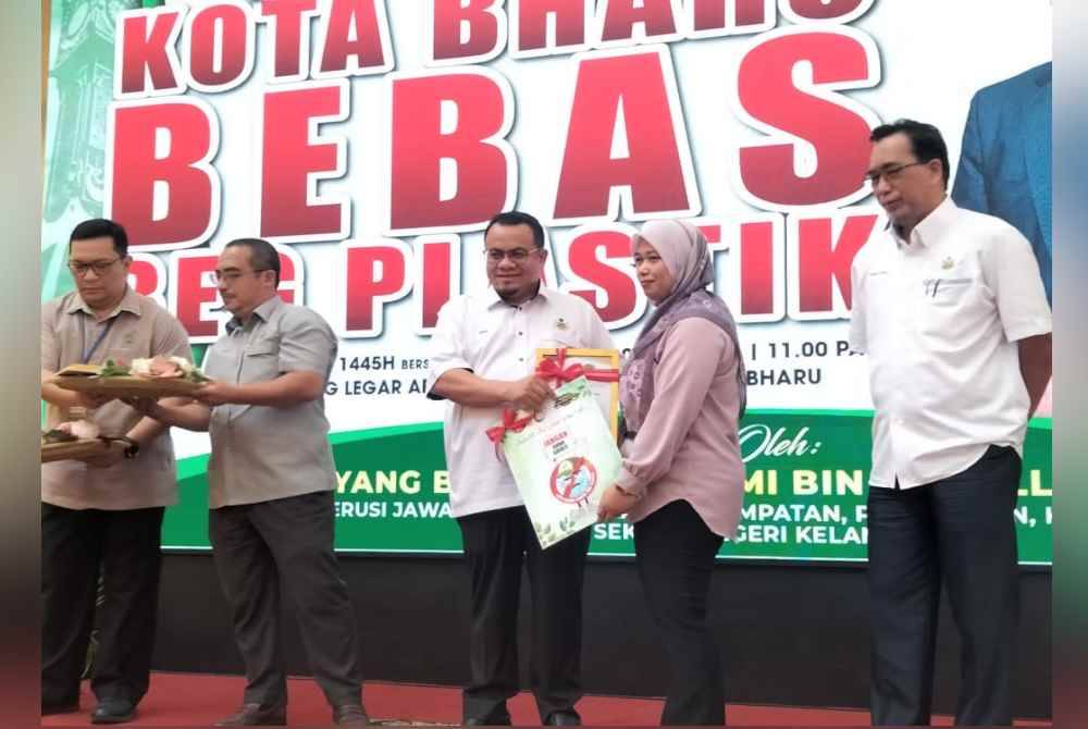 Hilmi (tengah) menyampaikan plak Kempen Sifar Plastik kepada wakil pasar raya di Kota Bharu pada Isnin.