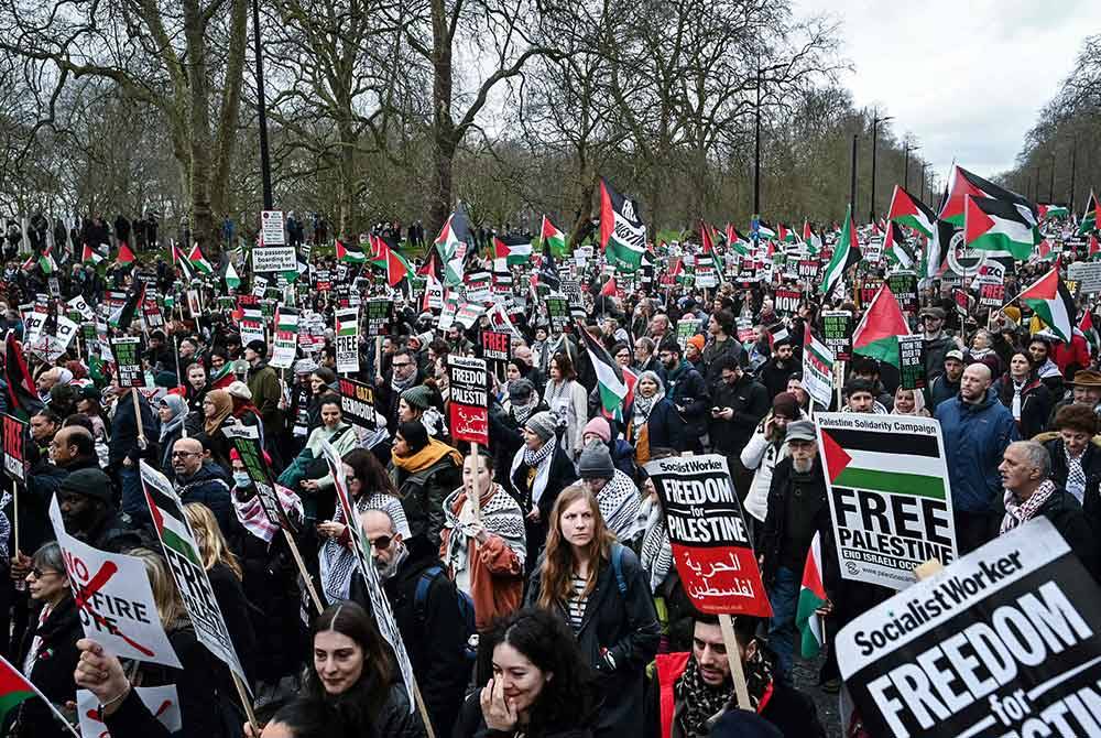 Aktivis dan penyokong pro-Palestin mengibarkan bendera dan membawa sepanduk semasa Perarakan Kebangsaan untuk Palestin di tengah London. - AFP