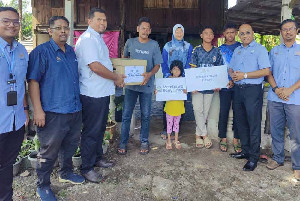 Ismail (dua dari kanan) menyampaikan sumbangan PERKESO kepada Riduan (empat dari kiri) pada Penyampaian Skuad Prihatin PERKESO di rumah waris pencarum di Kampung Parit 10 Gambut Sungai Besar di sini pada Rabu.