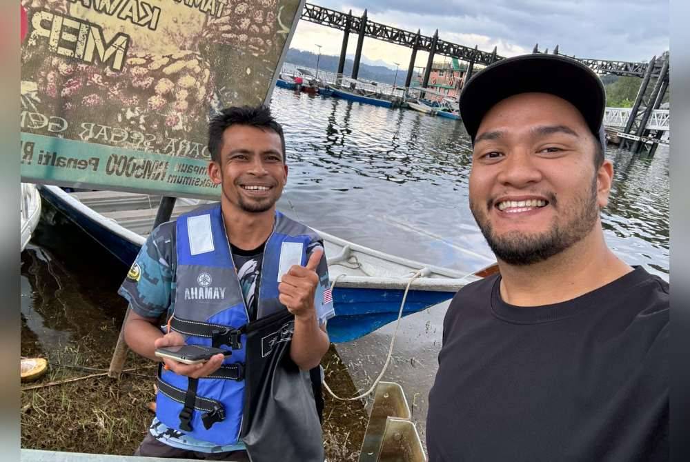 Azizan (kiri) menyerahkan dompet Muhammad Ikram ketika bertemu di Jeti Aman Jaya, Pulau Banding.