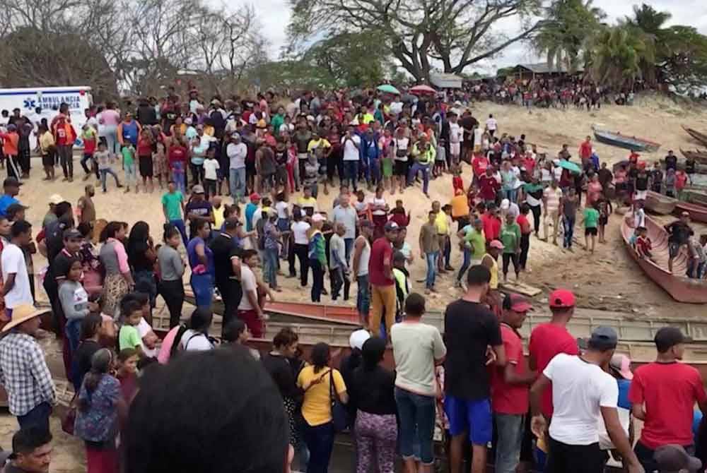 Orang ramai dan ahli keluarga mangsa berkumpul di tebing Sungai Guacara bagi menunggu berita perkembangan terkini tragedi tanah runtuh di lombong emas haram di La Paragua, Bolivar. Foto Agensi